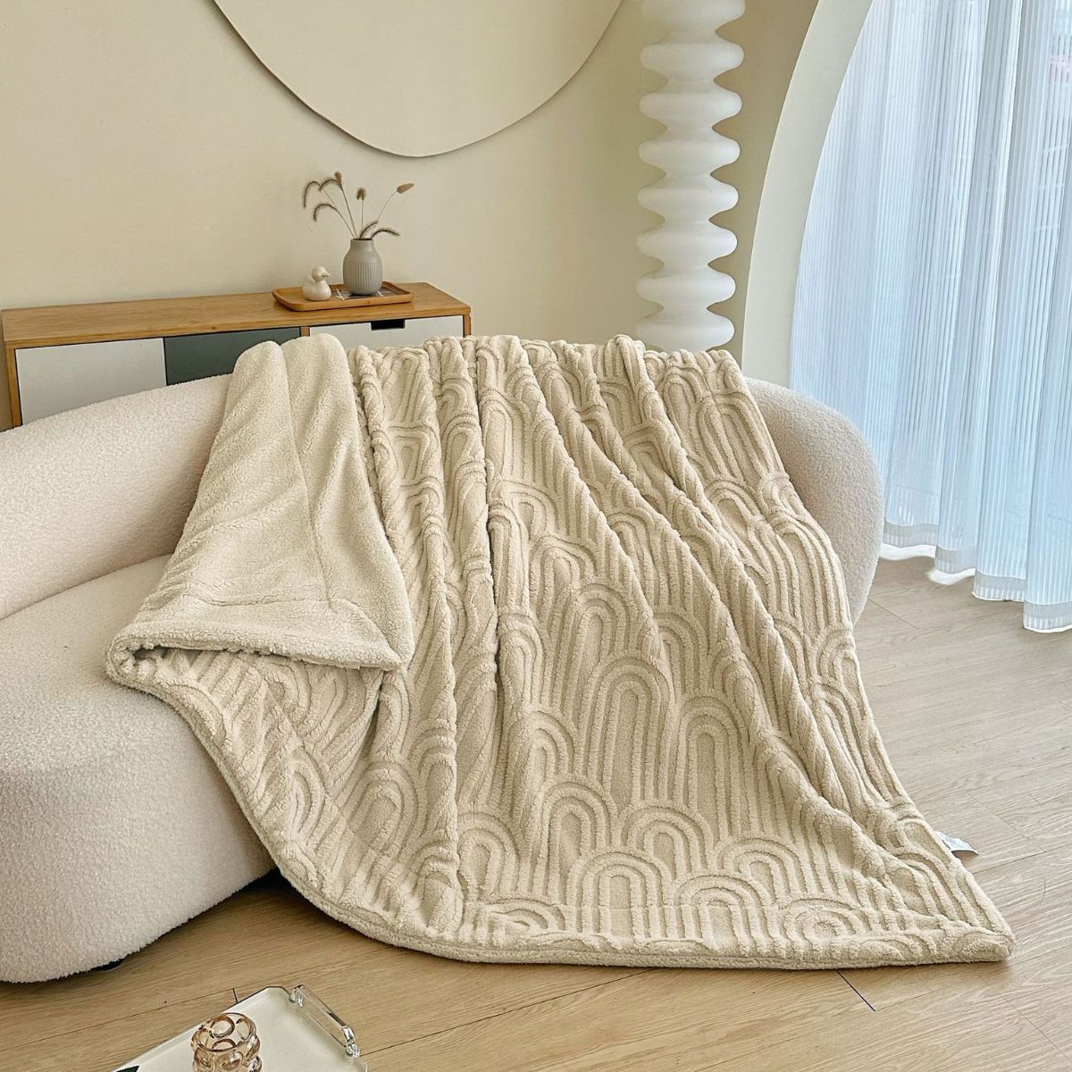 Soft beige fleece throw blanket with raised arch pattern on sofa
