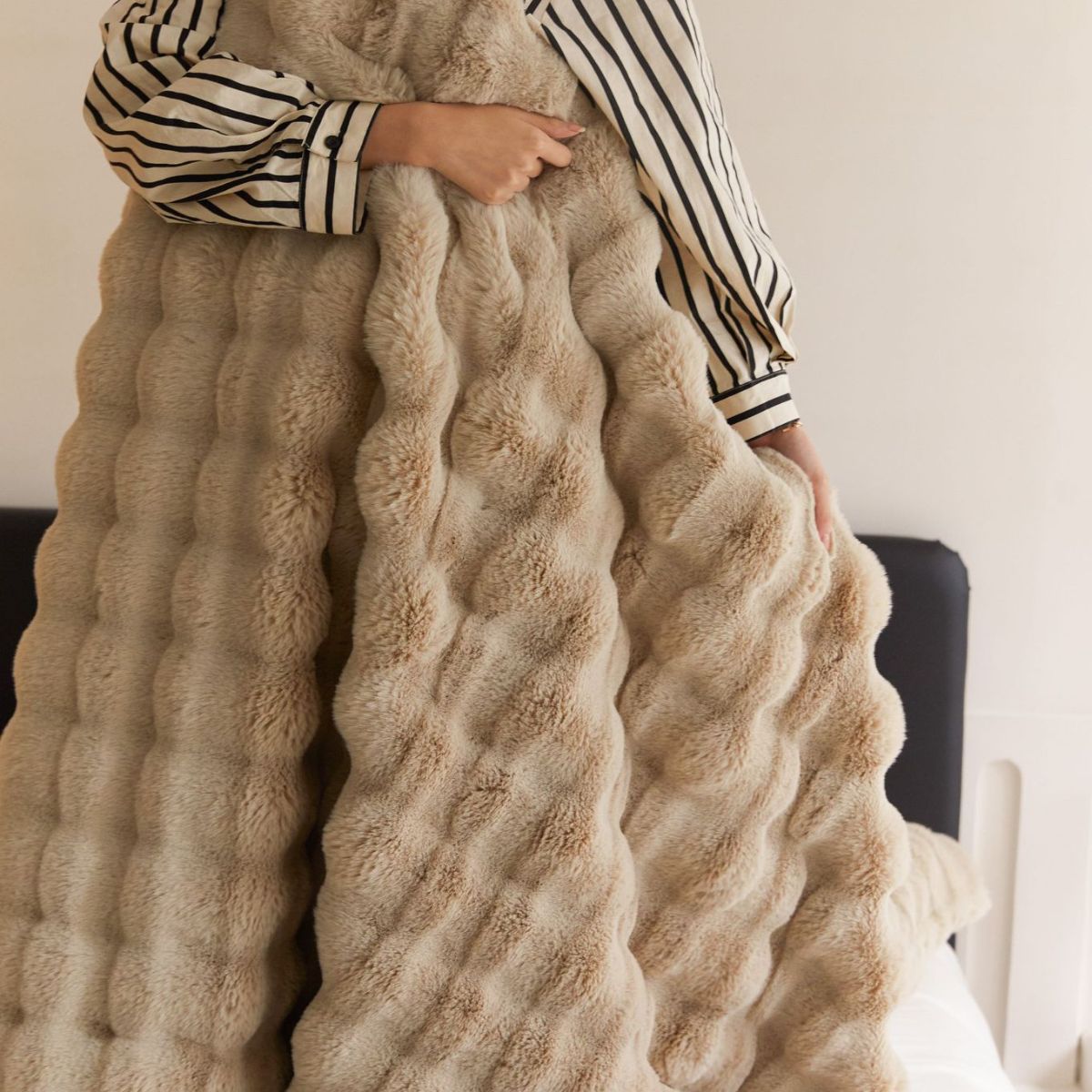 Caramel-colored fleece blanket with bubble texture, held in hand to show thickness and softness