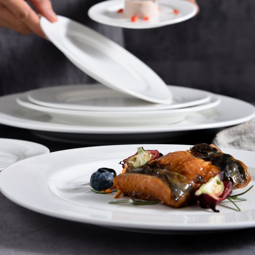 Close-up of grilled salmon dish on white plate with layered stack in background