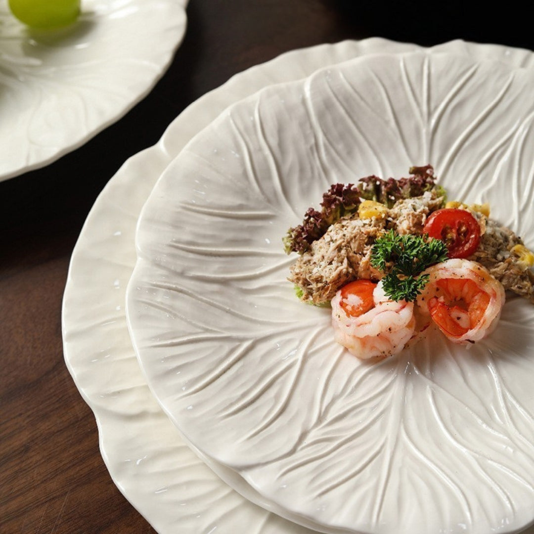 Close-up of ceramic leaf plate with shrimp and salad on wooden table