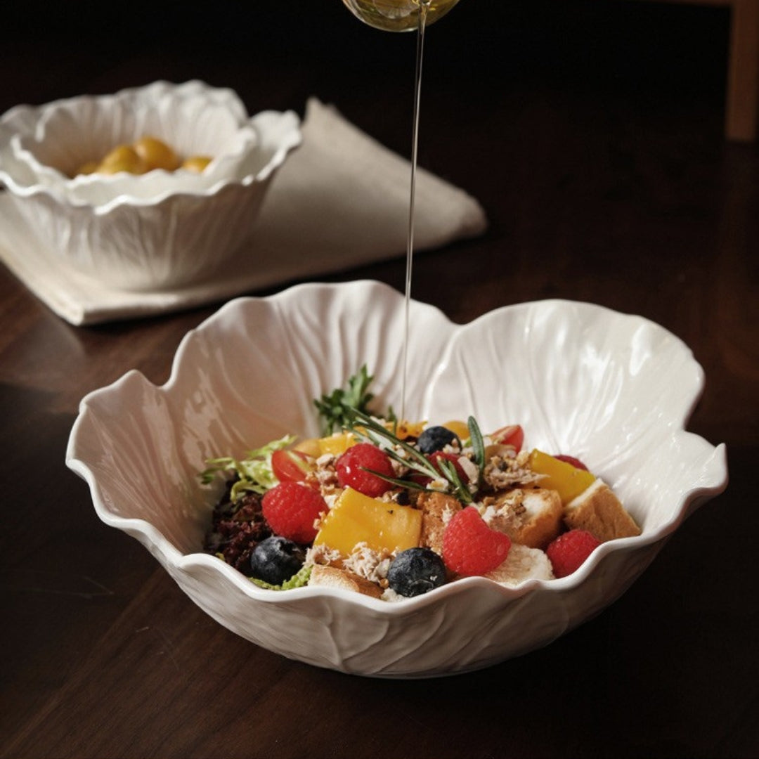 Pouring dressing onto salad in large white lettuce-shaped bowl