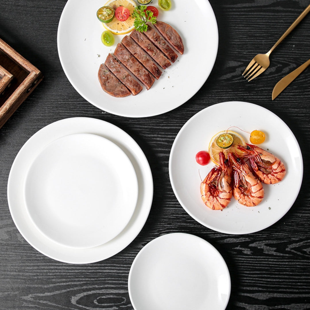 Overhead view of black table with multiple white ceramic plates and food