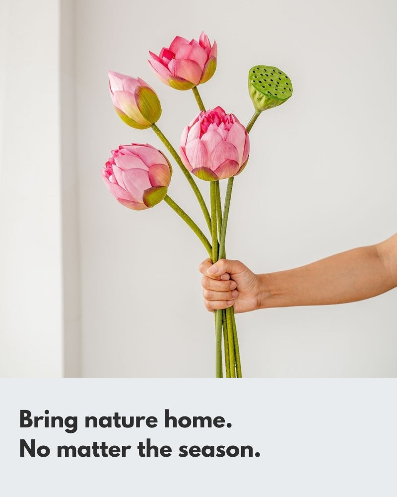 A hand holds a lifelike pink artificial lotus bouquet, featuring buds, blooming flowers, and a seed pod. The image highlights the realistic detail and soft colors of the bouquet against a clean white background, perfect for home decor.