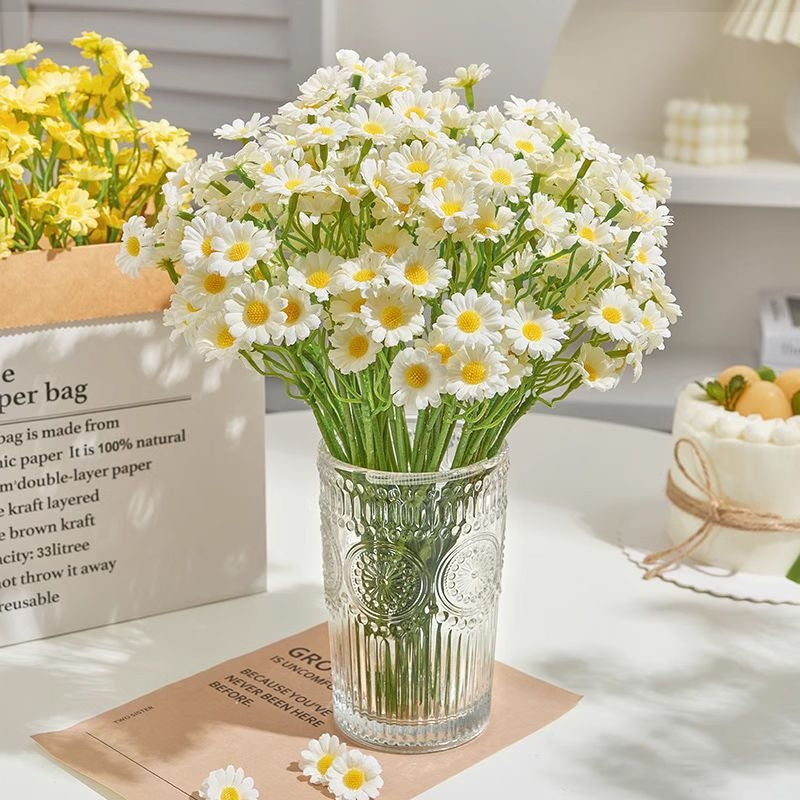 Artificial white daisy flowers arranged in a glass vase for home decoration