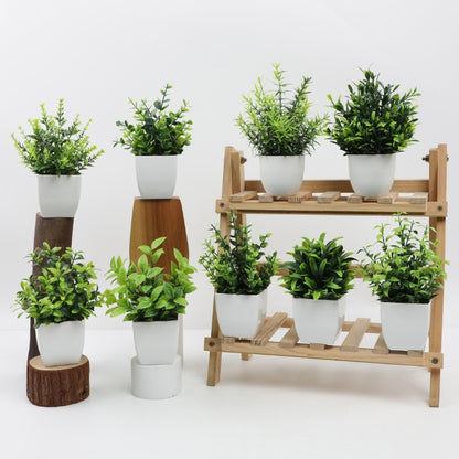 Artificial potted plants in white pots arranged on table and wooden stands for decoration