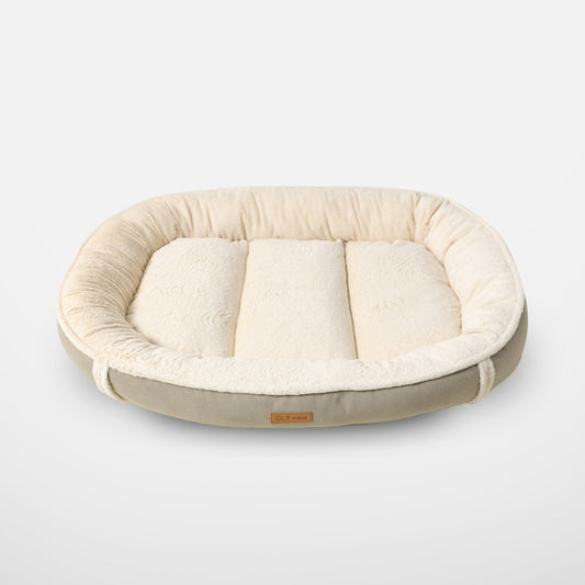  A full-view product shot of a comfortable, plush beige oval pet bed with raised sides and a soft fleece interior, isolated against a neutral background.