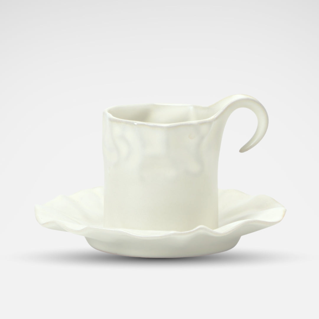White ceramic coffee cup with a sculpted wavy edge and artistic handle, viewed from above.