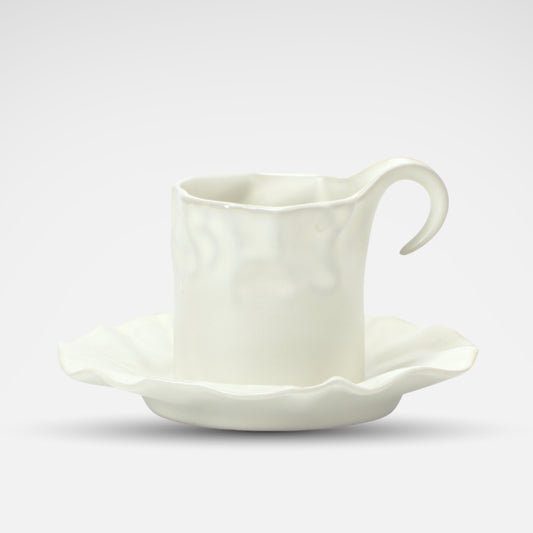 White ceramic coffee cup with a sculpted wavy edge and artistic handle, viewed from above.