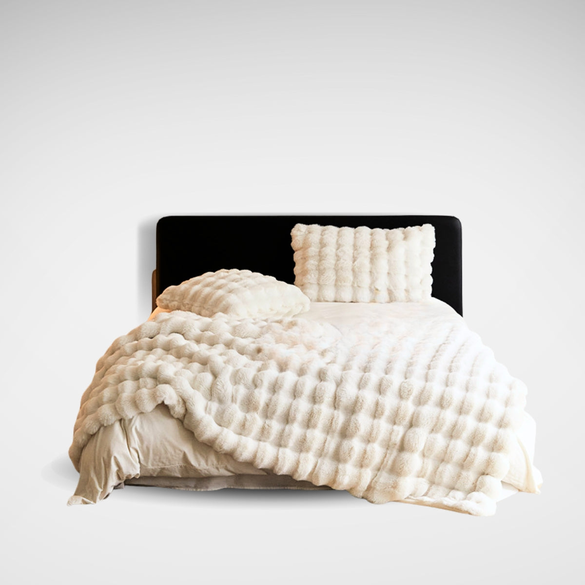 Full product view of cream bubble fleece blanket and pillow set on bed