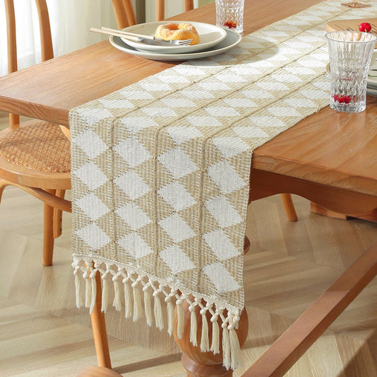 Diamond pattern beige and white woven table runner with tassels on wooden dining table