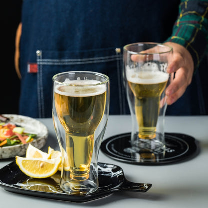 A lifestyle photo of two double-wall beer glasses on a modern black tray, accompanied by fresh lemon slices and a salad.