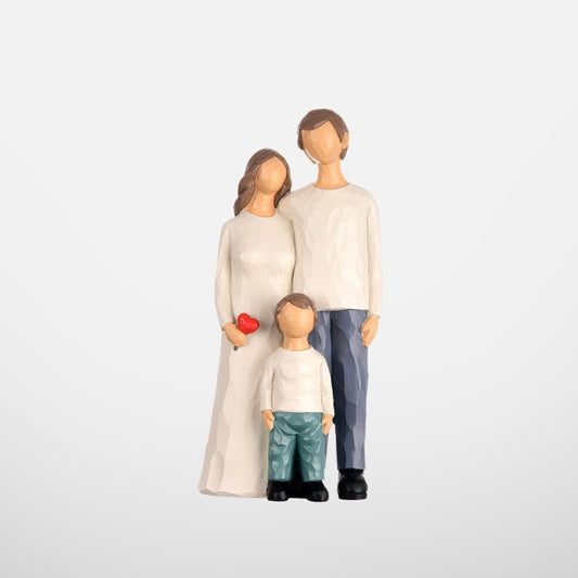 A family figurine featuring a father, a mother holding a red heart, and their young son, standing together on a clean white background.