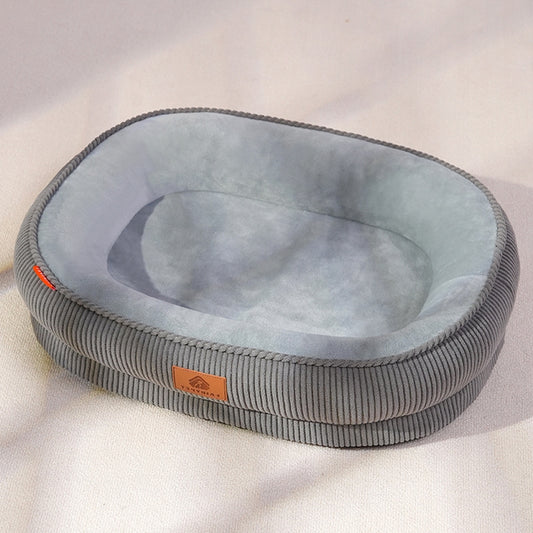 A cozy gray oval pet bed with a corduroy texture, placed on a light-colored floor, showing its modern design in a natural home environment.