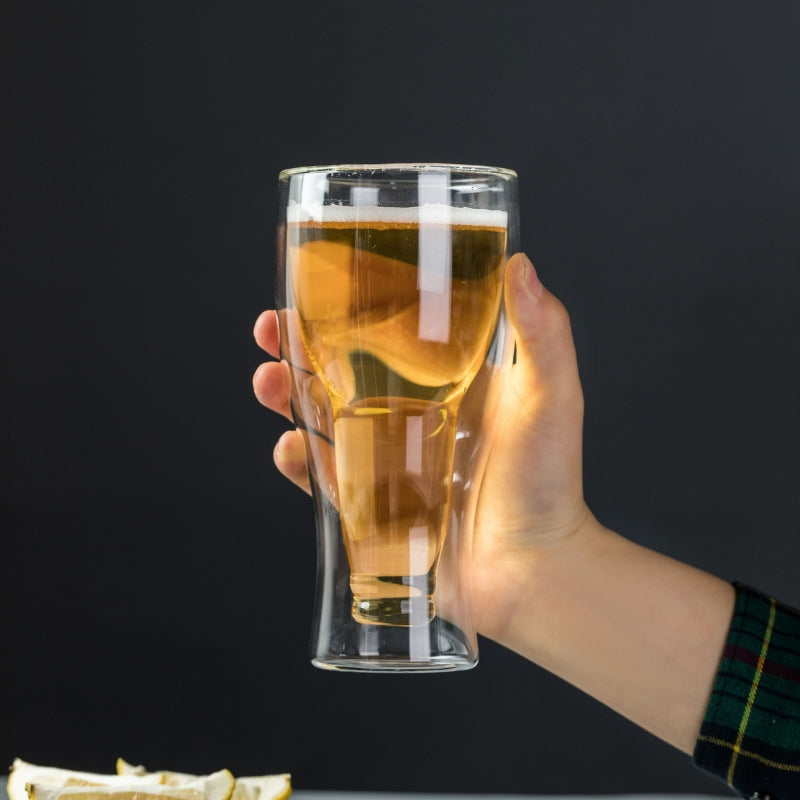  A hand holding the double-wall glass, with light shining through to highlight the clever beer bottle-shaped inner wall.