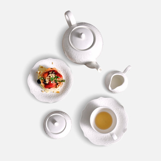 JUN HUA white ceramic tea set flatlay with dessert plate, teapot, milk jug and cup.