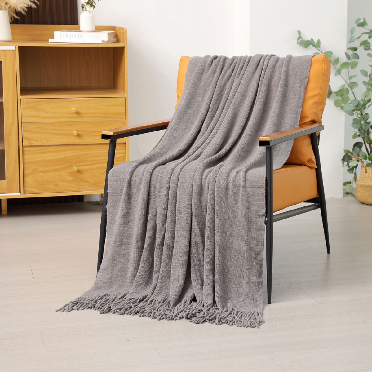 Dark gray tassel throw draped over armchair for modern interior