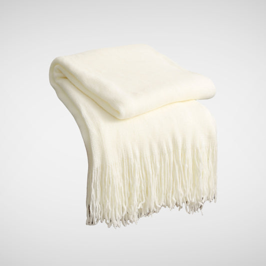 Cream knitted throw blanket folded neatly with tassel detail