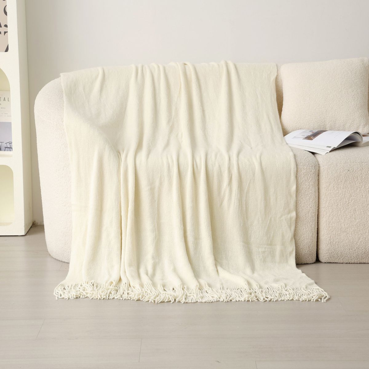 Cream tassel throw laid over white boucle sofa