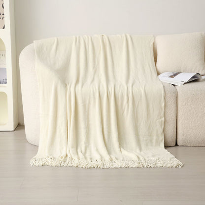 Cream tassel throw laid over white boucle sofa