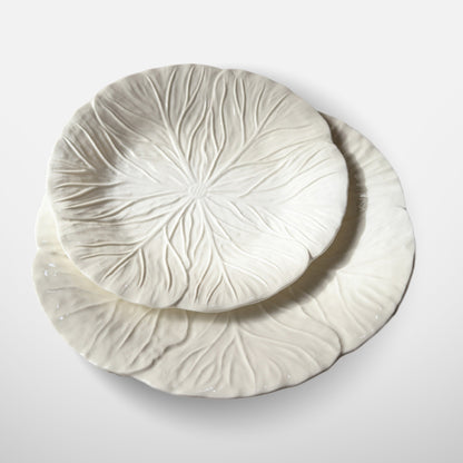 Angled view of two white ceramic leaf plates stacked together
