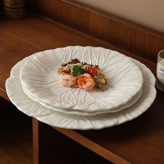 White leaf ceramic plates with food served, placed on wooden table