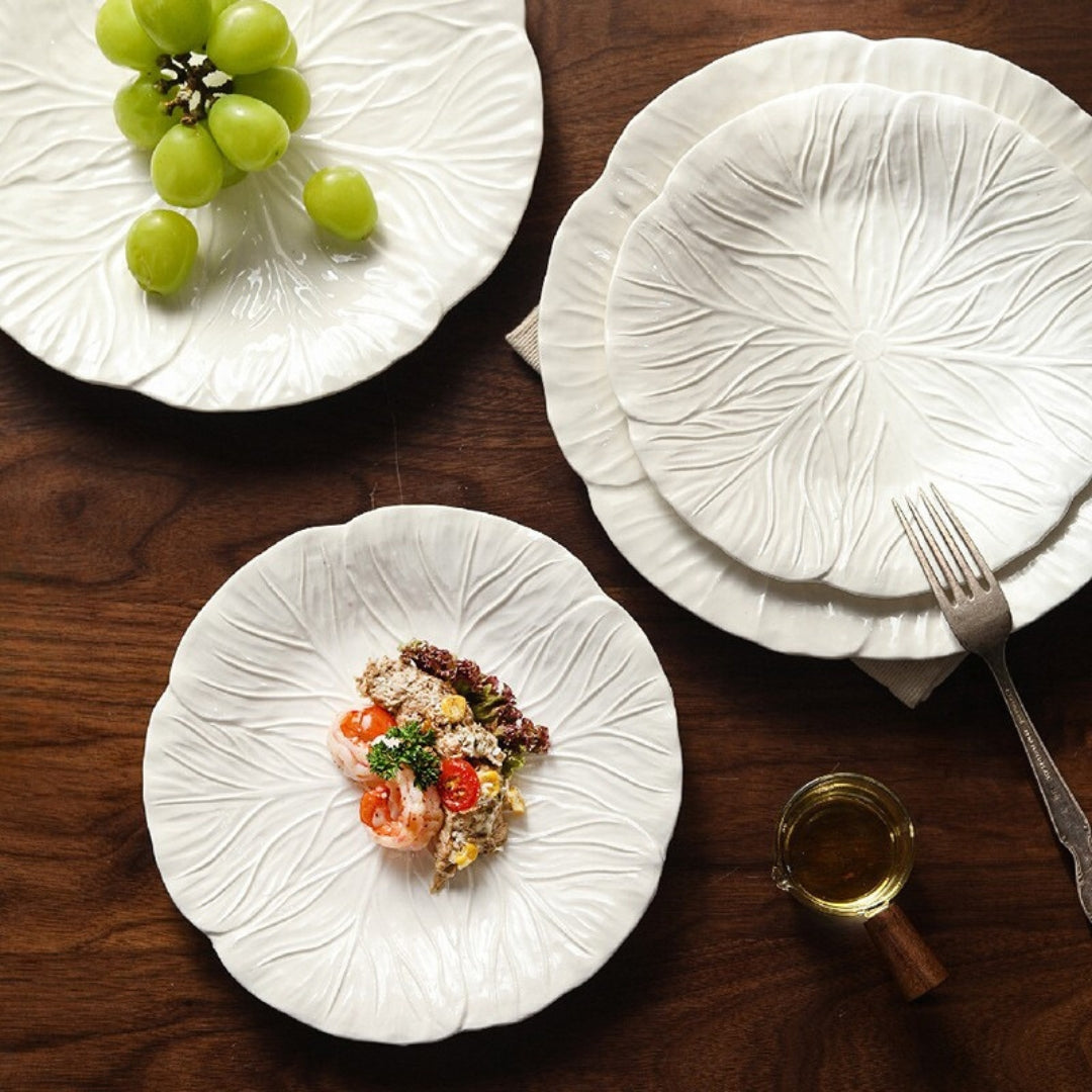 Overhead view of multiple ceramic leaf plates with food and fruits