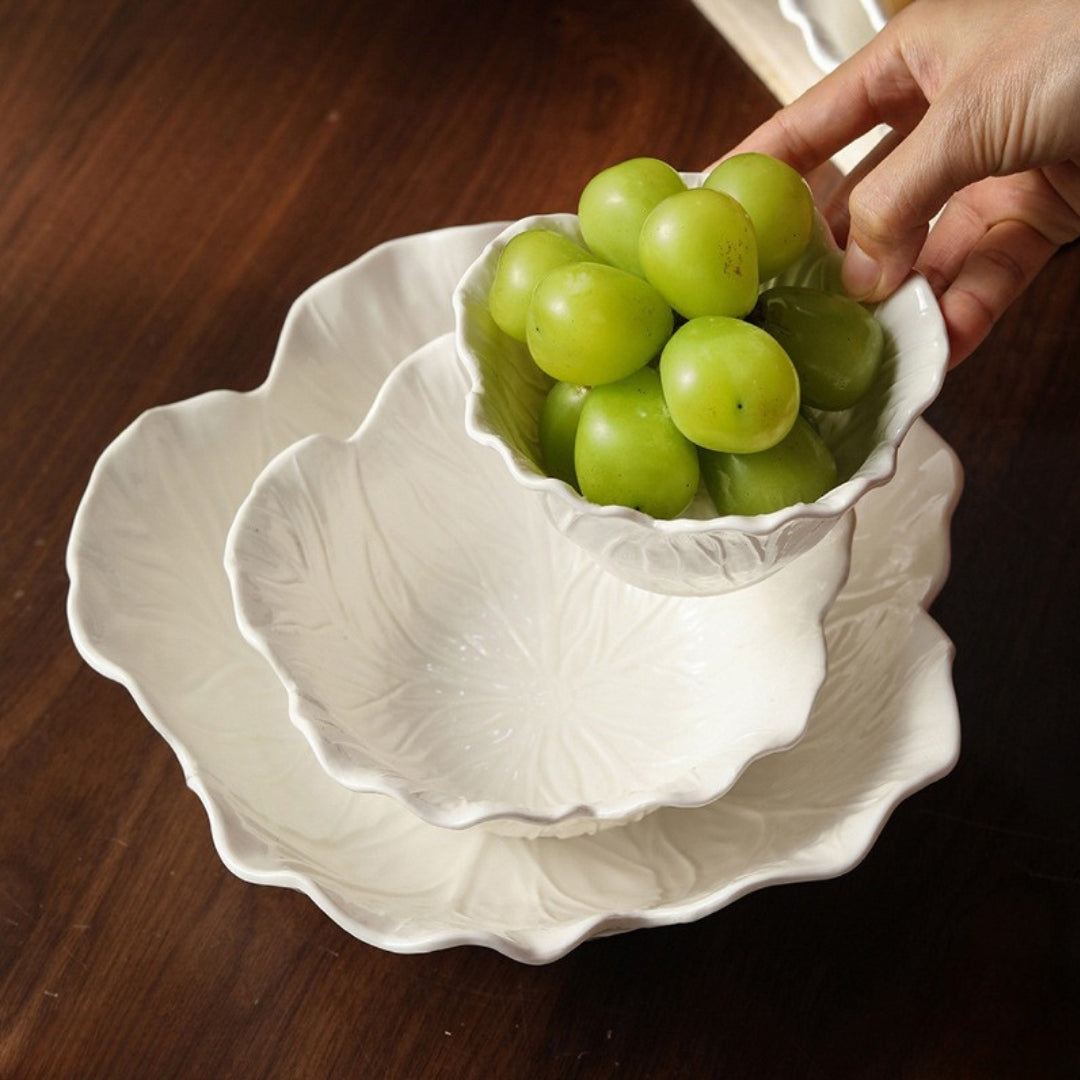 Hand holding white ceramic bowl filled with fresh green grapes