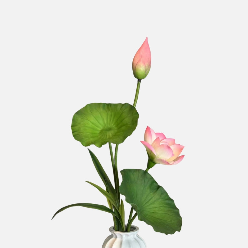 Artificial lotus arrangement with a pink bloom, closed bud, and green leaves in a white vase