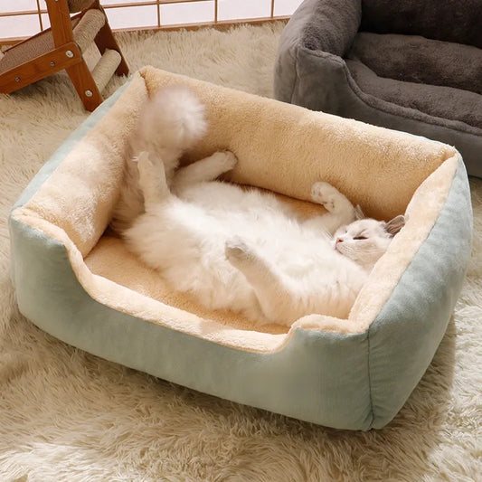 A white fluffy cat happily resting on its back inside a soft, mint green plush pet bed, showcasing the product's comfort and appeal.