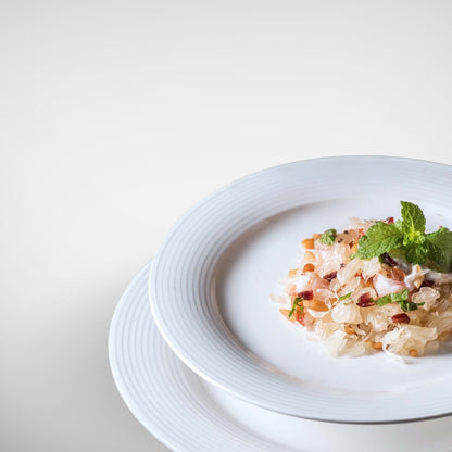 Angled view of layered white plates with salad, clean modern table setting