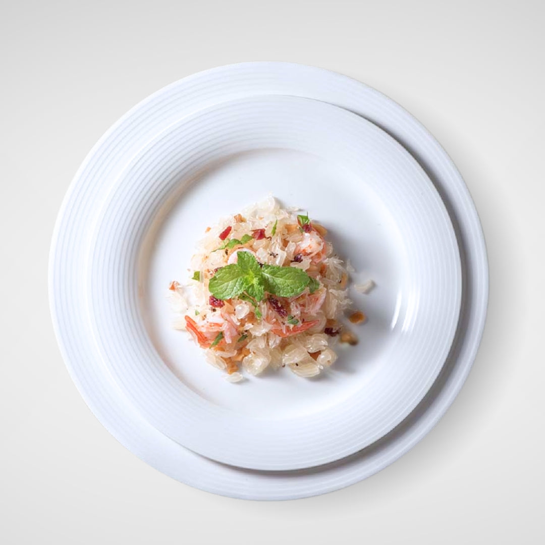 Top view of food served on stacked white plates with textured rim