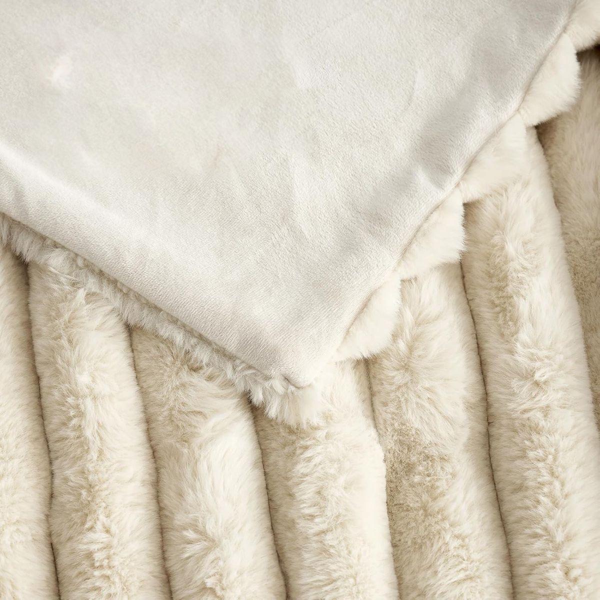 Cream throw blanket styled on a bed