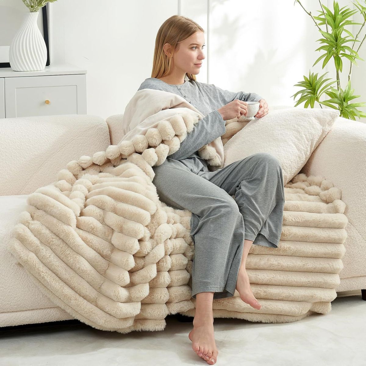 Lifestyle image of woman lounging with cream throw