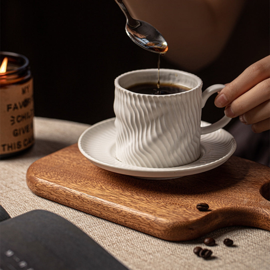 Coffee being poured into ripple ceramic cup, minimal morning setup.