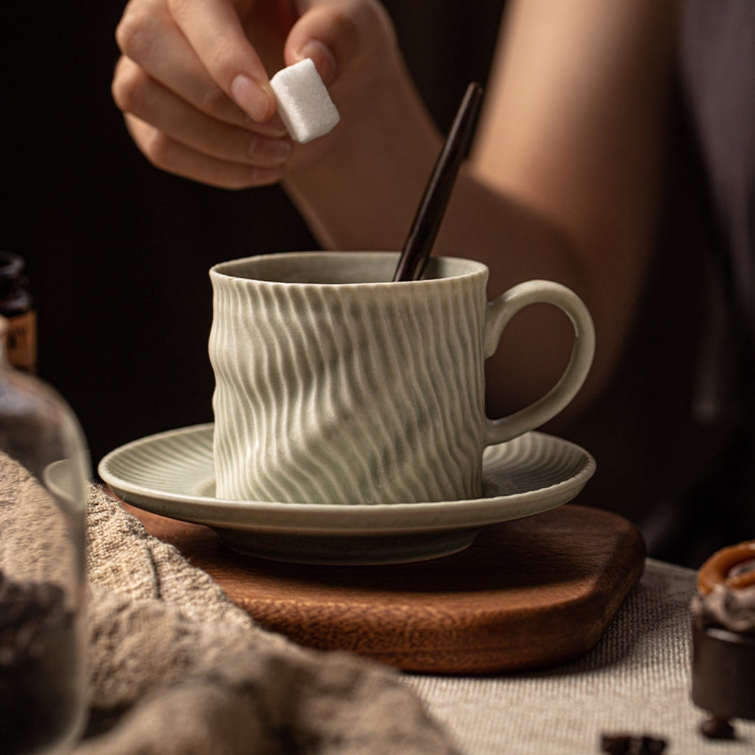 Hand holding ripple-texture white ceramic cup filled with coffee.