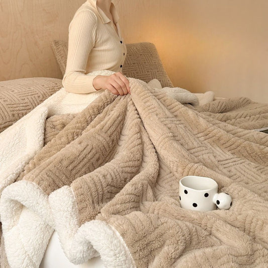 Beige throw blanket spread over bed with coffee mug and fleece interior visible