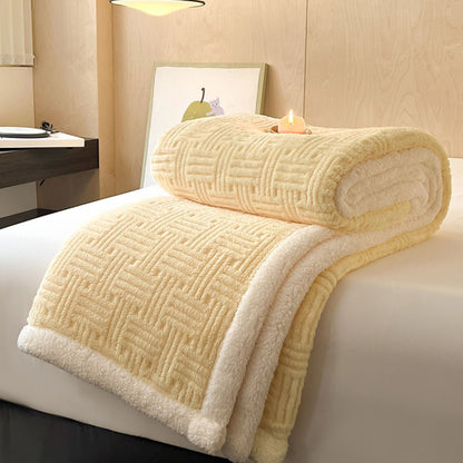 Yellow fleece-lined blanket rolled on bed with lit candle and modern decor